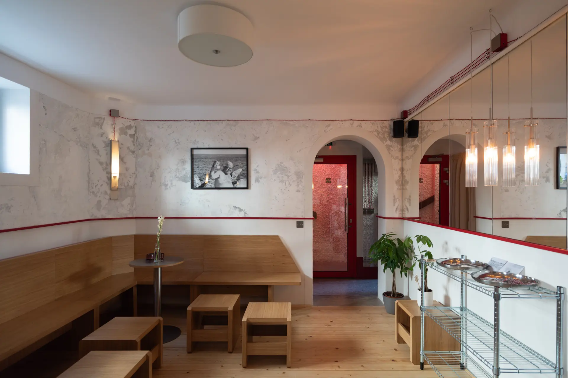 Sala cafenelei cu banchete din lemn, brâu roșu și oglinzi